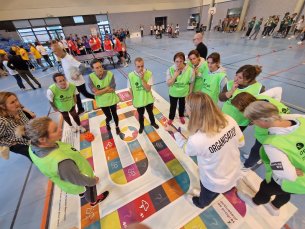 L'équipe verte regroupée en cercle, relève le challenge du jeu de plateau handipoursuite en format grandeur nature durant le challenge parasportif handi'hauts'lympics organisé par l'Agefiph