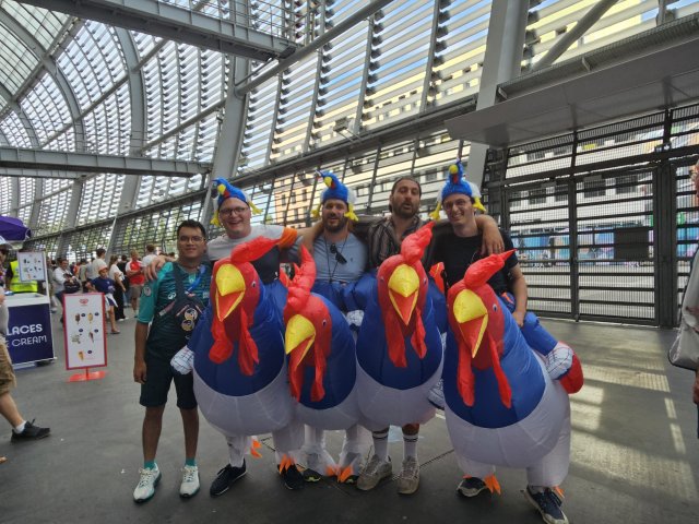 Michel à la gauche de l'image pose avec quatre supporters français déguisés en coq de la tête au pied