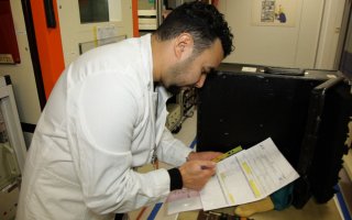 Un homme en blouse blanche, se penche sur des dossiers de métallurgie