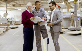 Trois personnes, dont une personne amputée, discutant dans un dépôt industriel