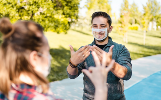 Deux personnes portant des masques inclusifs discutent en langue des signes
