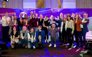 Photo prise lors de la remise de prix Activateurs de progrès 2023, le 27 mars 2023 lors de l'URRH à Bordeaux. L'ensemble des lauréats pose sur la scène, avec les trophées à la main. Sont également présents sur scène les animateurs de la soirée et des représentants de l'Agefiph dont le président et le directeur général.