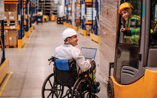 Photo représentant un espace de stockage de colis, sur laquelle sont représentés 2 employés, dont l'un est en fauteuil roulant.