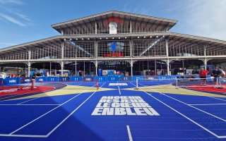 Plan large de la hallle de la villette au couleur du Club France. Au premier plan se trouve un terrain multisport bleu avec une inscirption au sol en majuscules et en blanc : "Au cœur des Jeux, le cœur en bleu"